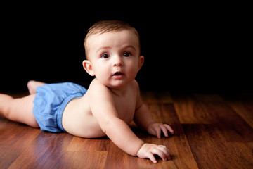 Naklejka premium Happy Baby Boy Lying on Wood Floor - Color Portrait