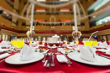 Beautiful flowers are placed on the table covered with red tablecloth, wedding hall