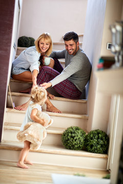 Girl with parents playing and holding teddy bear