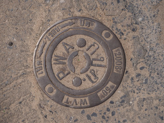 Manhole cover on pavement with patterns. Thailand.