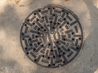 Manhole cover on pavement with patterns. Thailand.