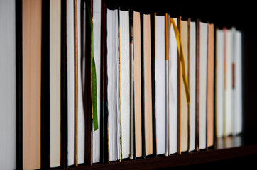 Lots of colourful thick open books stand on a dark background