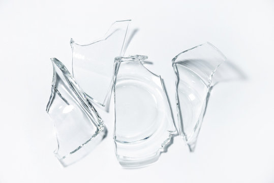Parts of the broken cup jar glass isolated on white background. Pieces of sharp broken glass. Concept of danger.