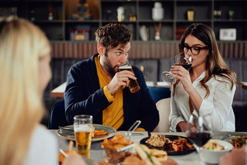 Two attrective friends sitting at restaurant and drinking wine and beer.