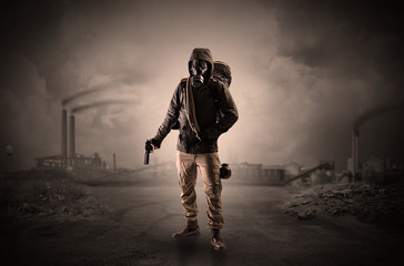Gas masked survival man coming with arms on his hand  in a demolished dark environment 
