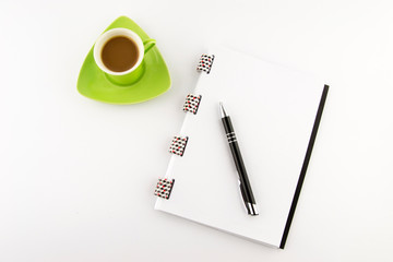 Coffee in a green cup with  notes and pencil on a white background. Top view.