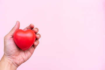 Men Hand holding Red Heart,Concept of Love and Health care,family insurance.World heart day, World health day.Valentine's day.isolated shape of heart on pastel pink background.
