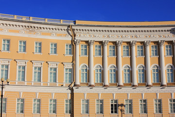 Historic building of yellow and white color with ornamental facade decor, classic pillars and symmetrical windows 