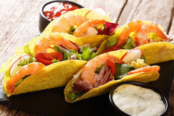 Fresh corn tacos with shrimps, fresh vegetables and sauces close-up. horizontal