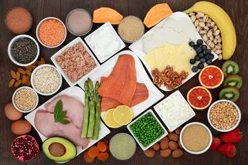Fototapeta na wymiar Health food for body builders high in protein including fish, meat, dairy, dietary supplement powders, pulses, grains, fruit, vegetables, seeds and nuts. On oak wood background.
