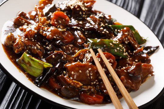 Asian pork roast with mun mushrooms and vegetables in a sweet and sour sauce closeup on a plate. horizontal