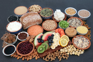 Large vegan health food collection on slate background. Super foods high in antioxidants, protein, vitamins, anthocyanins and dietary fibre.
