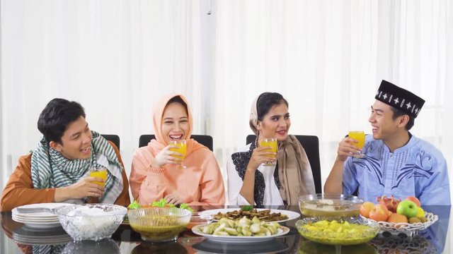 Group of young muslim people breaking the fast together in dining room at home while wearing islamic clothes. Shot in 4k resolution