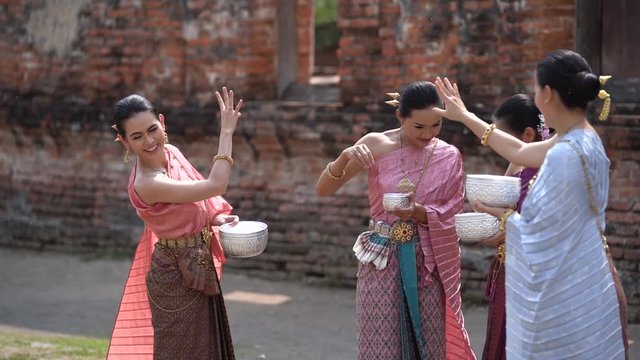 Songkran festival in Thailand. Happy Thai girls in Thailand cultural costume play water in the Thai new year festival called Songkran day. (Slow motion video)