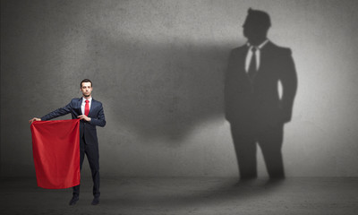 Businessman standing with red cloth on his hand and his shadow on the background
