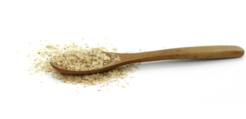 Wheat germ, the highly nutritious heart of the wheat kernel isolated on white. Wheat germ pile with wooden spoon isolated on white background, top view.