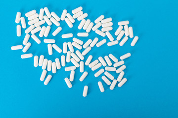 White pills on the blue paper background 