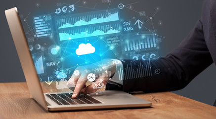 Businessman hand typing on laptop with reports and graphs concept around
