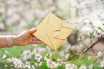 Close-up woman hand holding invitation card golden color, front view