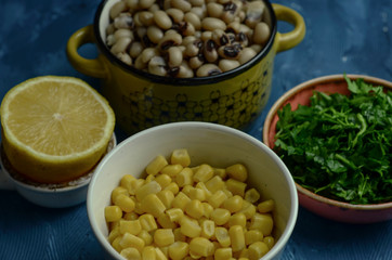 Dry cowpea salad ingredients; cowpea, lemon, parsley on blue background. Vegetarian food concept