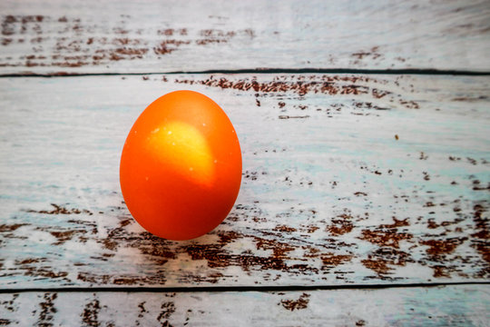 Orange eaaster egg on wooden background closeup
