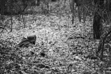 Re-enactor Dressed In Overcoat As German Wehrmacht Infantry Soldier In World War II Hidden In Ambush In Autumn Forest. Photo In Black And White Colors. Soldier Of WWII WW2