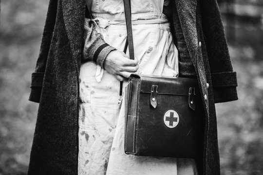 Re-enactor Wears Historical German Nurse Paramedic Of World War II Uniform With First Aid Kit. Photo In Black And White Colors. WWII WW2