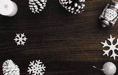 Top view on nice Christmas gift wrapped in white gift paper, Christmas tree decorations on dark wooden background. New Year holiday