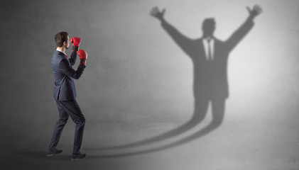 Businessman with boxing gloves fighting with disarmed businessman shadow
