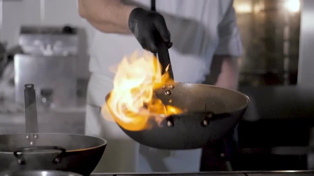 Chefs cooks and doing flambe on vegetables in wok on restaurant kitchen - Powered by Adobe