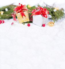 Christmas background with a red ornament, golden gift box, berries and fir in snow