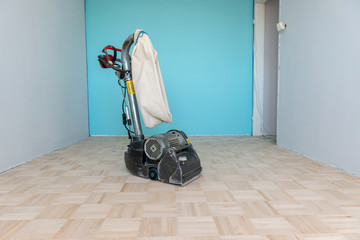 Sanding parquet floor with the grinding machine. Carpenter doing parquet wood floor polishing by...