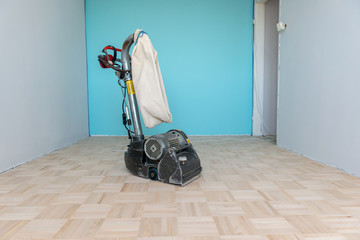 Sanding parquet floor with the grinding machine. Carpenter doing parquet wood floor polishing by grinding machine