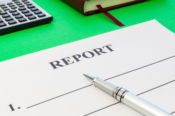Report with pen and calculator on green table.
