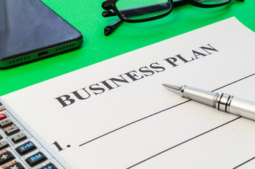 A business plan template to fill out with pen, glasses and calculator.