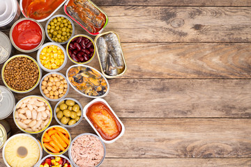 Canned food on wooden background, top view with copy space - obrazy, fototapety, plakaty