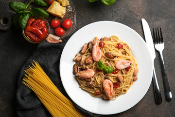 Seafood pasta and dried tomatoes in a creamy sauce with basil and parmesan on a dark background top view.