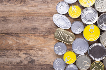 Canned food on wooden background, top view with copy space