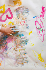Kid painting with colorful finger paint. Kind malt mit bunten Fingerfarben auf Papier.