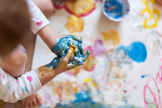 Child hands with blue finger paint. Kind malt mit flauer Fingerbarbe.