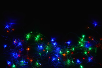 Colored lights (garland) in the dark. Bokeh effect Festive illumination.