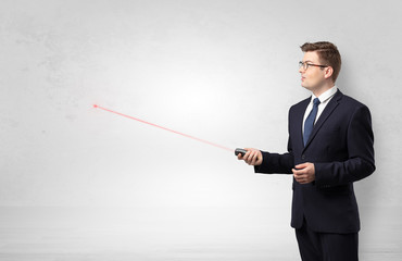 Young businessman with laser pointer and copyspace white wall
