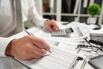 Businessman working at office and calculating finance, reads and writes reports. Business financial accounting concept.