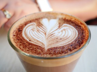 cup of coffee with cream on wooden background