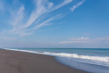 Fototapeta na wymiar Cloudscape and Volcanic Black Sand Beach and Blue Ionian Sea in Sicily