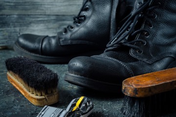 Old vintage leather boots with shoe brushes on wooden background