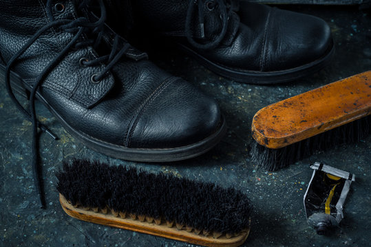 Old vintage leather boots with shoe brushes on wooden background