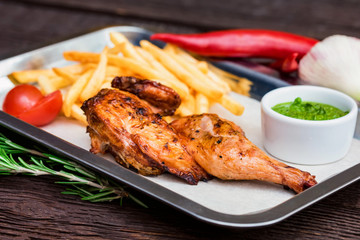 Close up meal with chicken thigh, french fries, chili pepper and garlic