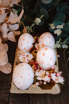 hand-painted easter eggs with pink dots in an egg cup with cherry blossoms and almond flowers