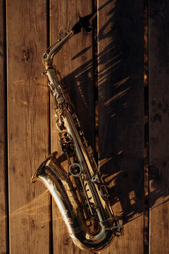 golden saxophone lying on an old wood shining in the sunlight